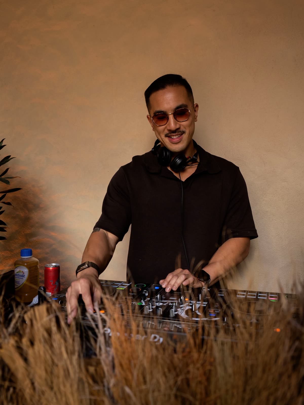 Sean Chi smiling behind the decks at a warm-lit event
